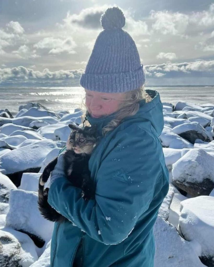 Frau haelt Katze im Schnee