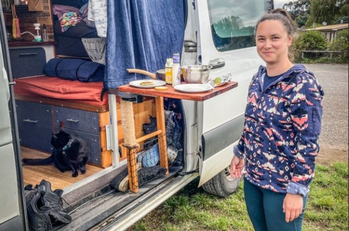 Katze und ihre Besitzerin neben einem Wohnwagen