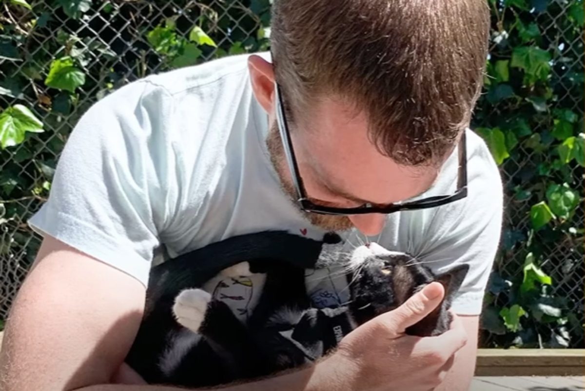 Mann haelt seine Katze im Arm